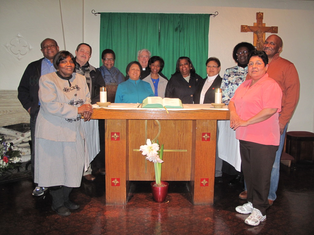 Twelve ministers gather around the altar at Our Lady of Refuge parish, Flatbush. They are, starting at left, Laurette Felix, Terrence Whiteman, Angel S. Cruz, Jennifer Baptiste, Celina Elvir, Father Michael A. Perry, Enid Blas Rosas, Faith King-Beckles, Nidia Rivera, Claire Marie Sejour, Antolin Ramon and Gloria Cruz. (Photo by Antonina Zielinska)