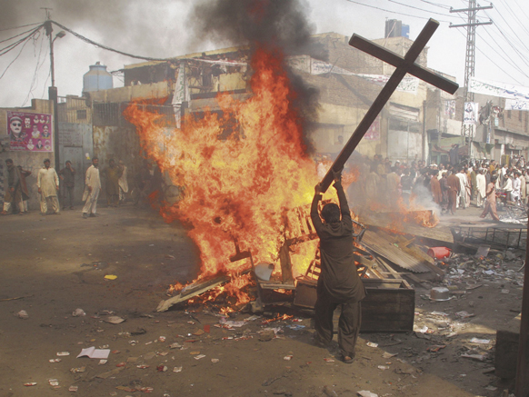 A demonstrator burns a cross during a protest in the Badami Bagh area of Lahore, Pakistan, March 9. The Catholic Church in Pakistan condemned a March 9 attack by an estimated 3,000 Muslims on a Christian colony in Lahore that left more than 175 buildings, including two churches and dozens of homes, torched and hundreds of people homeless.