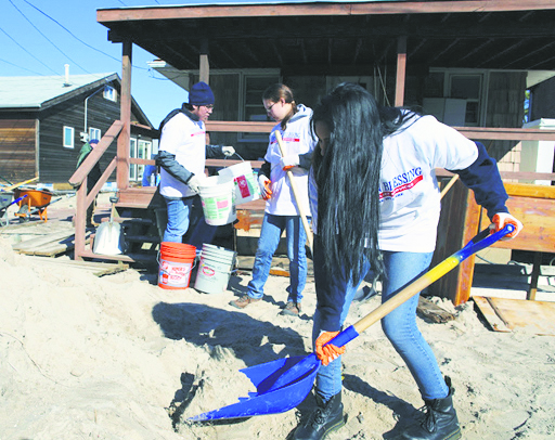 Volunteers from Archbishop Molloy help dig the sand out of Breezy Point. 