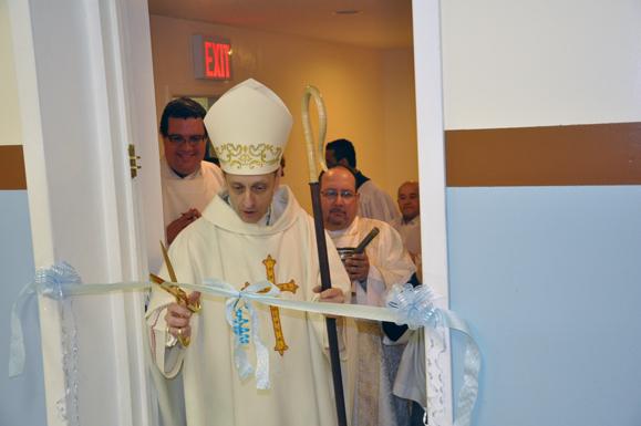 Bishop Caggiano cuts the ribbon to Three Kings Hall while Father Manuel Rodriguez, S.D.B., and Deacon Juan Carratini look on.