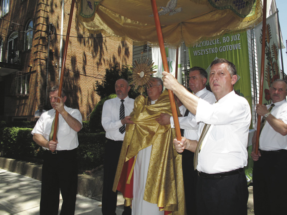 Bishop Nicholas DiMarzio blesses Borough Park and the people gathered for the outdoor Corpus Christi procession with the Body and Blood of Christ. The sign behind him that was prepared in one of the neighborhood homes says, “Come, for everything is now ready” (Luke 14:17).