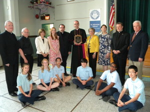 Auxiliary Bishop Paul Sanchez holds a plaque honoring Robert Cunningham as parish and diocesan officials look on at St. Sebastian’s School, Woodside. (Photo by Jim Mancari)
