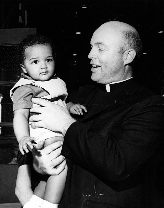 Father Sullivan, director of Catholic Charities, greets a young girl from child care services.