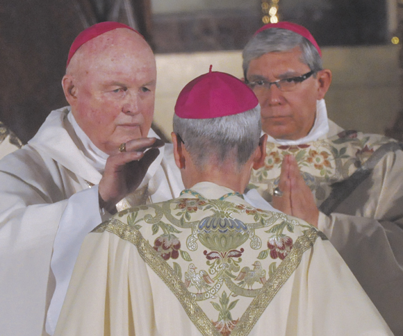He lays hands on the head of Bishop Paul Sanchez as he is ordained a bishop in 2012.