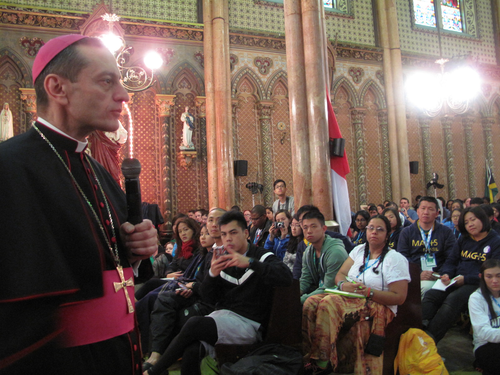 Below, Auxiliary Bishop Frank Caggiano shares his wisdom with English-speaking pilgrims during a catechesis session in Rio de Janeiro. After his prepared speech, he took questions from the audience. Although he joked that he would answer only easy questions, he spoke bluntly on homosexuality, abortion, and the reason behind calling the pope “holy.”