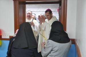 Earlier this year, Bishop Caggiano helped dedicate the Sister Jean and Sister Miriam Soup Kitchen at Epiphany Church in Williamsburg. Here he is shown applauding as the sisters cut the ribbon. Lending a hand is Deacon Juan Carattini of SS. Peter and Paul parish.