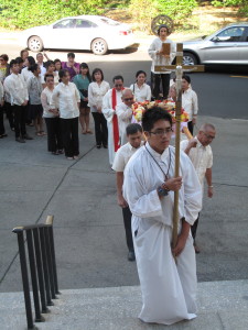 A statue of St. Lorenzo Ruiz, the first Filipino saint, follows the cross in a procession entering Mary’s Nativity Church, Flushing. 