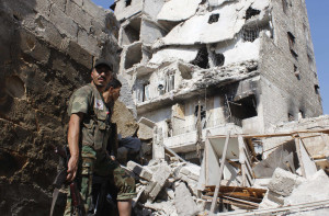 Free Syrian Army fighters stand in front of buildings damaged by shelling in Aleppo