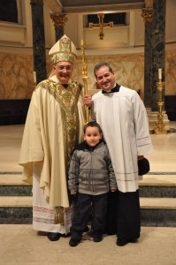 Bishop Nicholas DiMarzio with Deacon Jaime Varela, at left, and the deacon’s grandson, Adrian James Varela, at St. James Cathedral, Downtown Brooklyn.