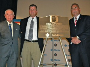  From left, St. Francis Prep varsity football head coach Vince O’Connor, Vince Lombardi’s grandson John Lombardi and Rutgers University head football coach Kyle Flood are pictured with the Vince Lombardi plaque that will hang in the Fresh Meadows school. (Photo by Jim Mancari)