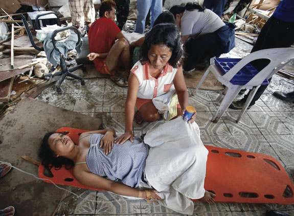 A woman comforts a pregnant relative having labor pains before she delivered a baby Nov. 11 at a makeshift birthing clinic in typhoon-battered Tacloban, Philippines. Super Typhoon Haiyan, one of the strongest storms in history, is believed to have killed tens of thousands, but aid workers were still trying to reach remote areas.