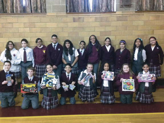 St. Pancras’ sixth graders, above, show the Christmas presents they purchased for two local children. They also purchased chickens for a struggling village through Heifer International.