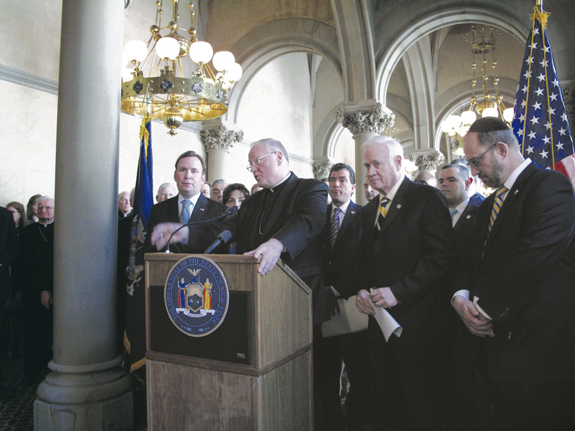 State Senator Martin Golden, right, and Assemblyman Michael Cusick flank Cardinal Timothy Dolan during a press conference at the State Capitol in Albany.  Below, Bishop Nicholas DiMarzio thanks Sen. Golden for his work on the Education Investment Incentive Act.