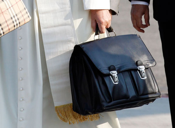 Pope Francis holds his personal bag as he boards a plane in July at an airport in Rome. People were stunned he was carting around his own carry-on bag.