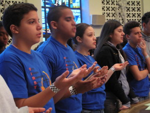 Youth say the Our Father during Mass