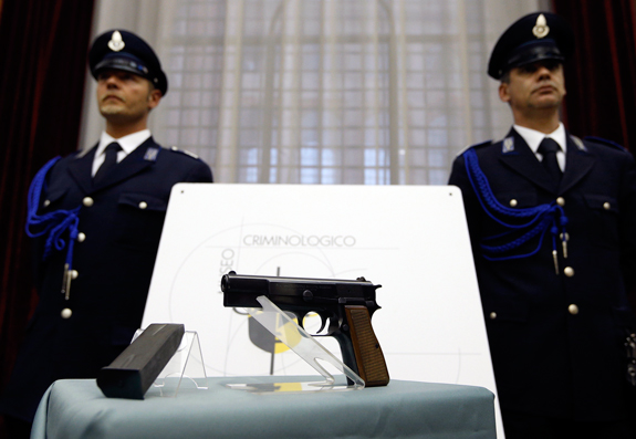  Italian police officers stand behind the Browning 9 mm caliber pistol used by Mehmet Ali Agca in the 1981 assassination attempt on Blessed John Paul II in Rome March 17. The weapon was shown to journalists before being transported to the John Paul II Museum in Wadowice, Poland, where it will be displayed for the next three years. 