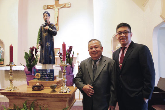 Huynh Thanh Nguyen and Phu Nguyen stand with a statue in 2013 of their ancestor, St. Matthew Nguyen Van Phuong, in a chapel at the Southeast Asian Vicariate campus in Portland, Ore. Each May, the family holds a Mass at the chapel in honor of the saint.