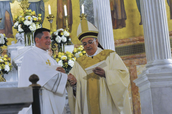 Bishop hands an assignment letter to Father Marcin Chilczuk.
