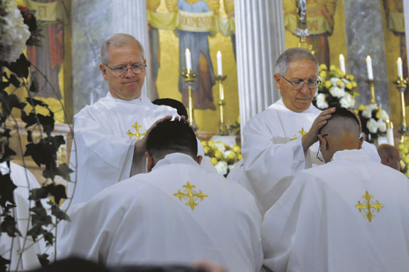 Father Thomas Pettei and Msgr. Fernando Ferrarese lay hands on the heads of the newly ordained.
