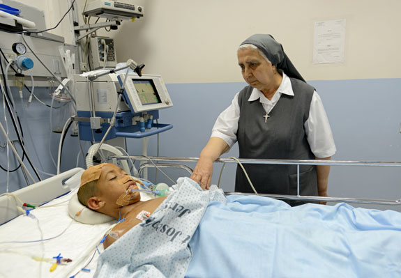 Above, Sister Gilbert Saliba, a member of the Sisters of St. Joseph of the Apparition, visits Nidal Alawi, 11, of Gaza in the intensive care unit of St. Joseph Hospital in Jerusalem. The boy is one of 23 Gazan patients being treated at the hospital, which specializes in head- and chest-trauma wounds.