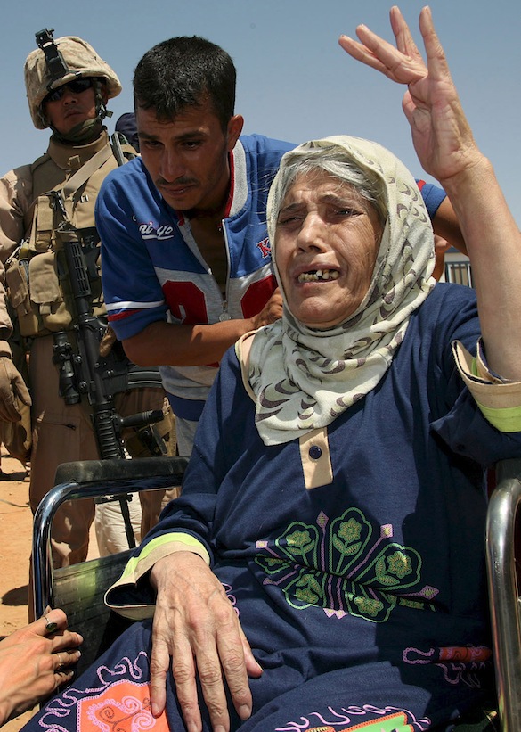 Elderly Iraqi woman fleeing violence gestures at refugee camp