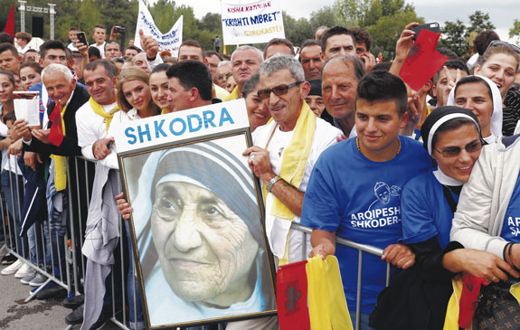 People in the crowd show off a photo of native Albanian Mother Teresa of Calcutta as they await the arrival of Pope Francis in Mother Teresa Square.
