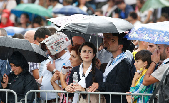 Crowds huddle under umbrellas as the congregation joins Pope Francis as he celebrates the Mass. 