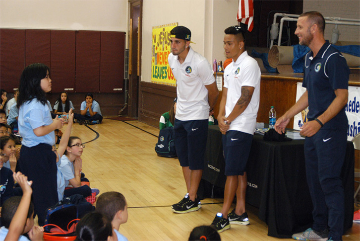 A student at Most Holy Redeemer Catholic Academy, Flushing, asks a question of New York Cosmos soccer players Sebastian Guenzatti and David Diosa, who visited the school to help kick off an exercise initiative on Sept. 24. (Photos © Marie Elena Giossi) 