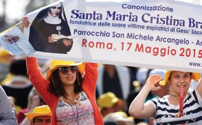 Young women hold a banner showing new Saint Maria Cristina Brando from Italy before the start of the canonization Mass.  The new saints are: Marie-Alphonsine and Mary of Jesus Crucified, both from historic Palestine; Jeanne Emilie De Villeneuve from France; and Maria Cristina Brando from Italy.  (Photo  Catholic News Service/Paul Haring)