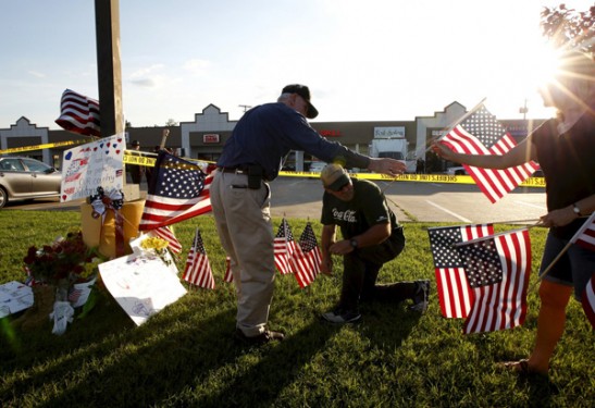 Mourners place flags at a makeshift memorial for shooting victims in front of the Armed Forces Career Center in Chattanooga, Tenn., July 16. The shooter, Mohammad Youssuf Abdulazeez, 24, was killed by police gunfire after he fatally shot four U.S. Marines and wounded three more people at two military offices that day in Chattanooga. (Photo © Catholic News Service/Tami Chappell, Reuters) 