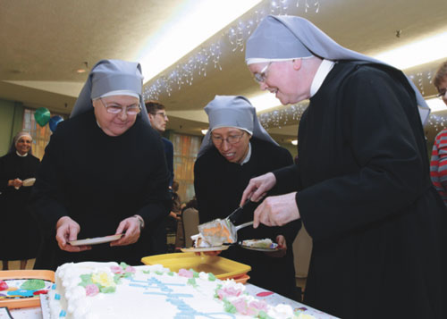  Sisters Carol Ferrucci, left, Maria Goretti Hung and Margaret Regina Halloran prepare to distribute cake at a birthday party for centenarians earlier this year at the Little Sisters of the Poor’s Queen of Peace Residence in Queens Village. Eight residents celebrating 100 or more years in 2015 were honored at the event. (Photo by Gregory A. Shemitz) 