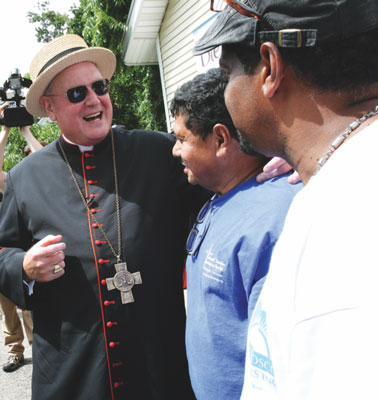Cardinal Timothy M. Dolan greets the workers during a visit to the workshop.