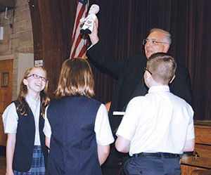 Bishop Nicholas DiMarzio holds up a Pope Francis doll presented to him by the students of St. Margaret School, Middle Village, during a visit to the school Sept. 18. Earlier that morning, he also visited Our Lady of Hope School nearby. (Photo by Marie Elena Giossi)