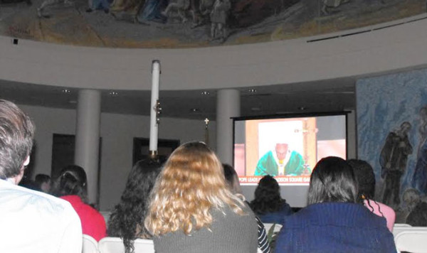 Students at St. John’s University, Jamaica, followed the papal Mass at Madison Square Garden on television that was set up in the foyer of St. Thomas More Church on campus. (Photo by Michael Rizzo)