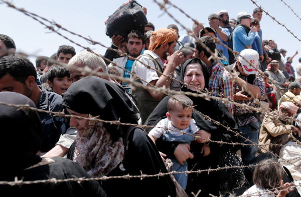 Syrian refugees wait on the Syrian side of the border near Sanliurfa, Turkey, June 10. Bishop Eusebio Elizondo, chairman of the U.S. Conference of Catholic Bishops' Committee on Migration, says the United States should welcome Syrian refugees and work for peace. (CNS photo/Sedat/Suna, EPA) 