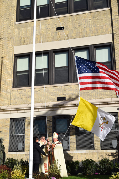 Barbara Reiter, St. Luke’s principal; Msgr. John Tosi, pastor; and Bishop Chappetto raise the Vatican and U.S. flags in front of the newly renovated school front.  (Photos © Maria-Pia Negro Chin)