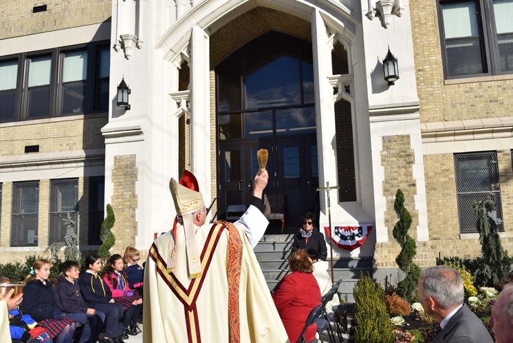Auxiliary Bishop Raymond Chappetto sprinkles holy water on the renovated facade of St. Luke School, Whitestone, on Nov. 13.  (Photos © Maria-Pia Negro Chin)