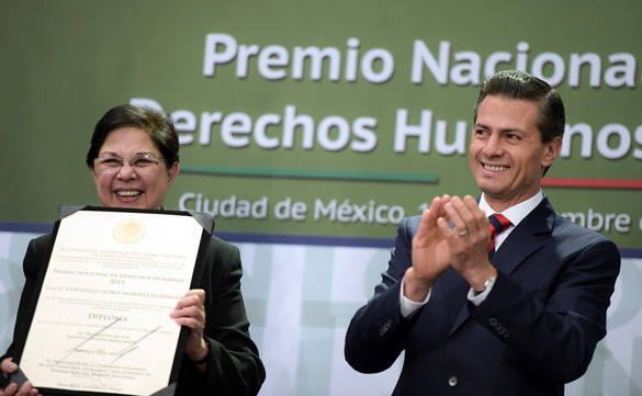 Mexican President Enrique Pena Nieto applauds after presenting Sister Consuelo Morales, a member of the Congregation of Our Lady: Canonesses of St. Augustine, with Mexico's national human rights award Dec. 10 in Mexico City for her work with the families of disappeared persons. (CNS photo/Presidency of the Republic) 