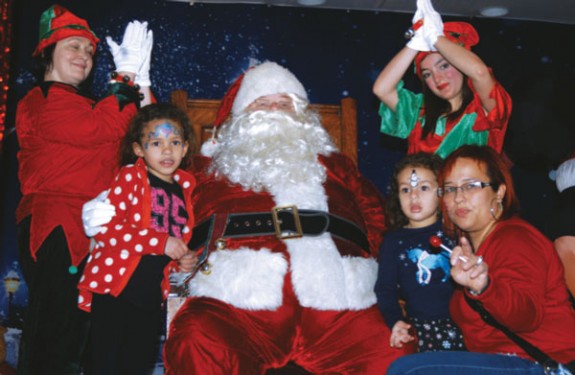 Santa Claus and his elves pose for a photo with Sandra Ruiz and her two daughters. Ruiz, a parishioner at Our Lady of Perpetual Help, Sunset Park, said the experience was something she and her children will never forget.