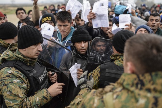 Migrants and refugees show their ID papers to Macedonian police Nov. 20 and wait to cross the Greek-Macedonian border near Gevegelija, Macedonian. The extensive vetting process that all refugees undergo before arriving in the United States, "screens out any possible threat of terrorism," said the executive director of the U.S. bishops' Migration and Refugee Services. (CNS photo/Georgi Licovski, EPA) 