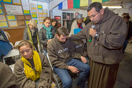Franciscan Brother Juan Turios of Action Network prays in 2013 with immigration reform advocates in Washington. To help appreciate and better promote the vocation of religious brothers, the Vatican released a 50-page reflection on the importance of their life and mission of evangelization, fraternity and sacrifice. (Photo by Catholic News Service/Jim West)