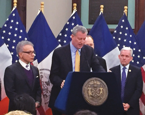 New York City Mayor Bill de Blasio addresses the crowd Jan 5, the day he signed a bill that would allow non-public schools with more than 300 students to get reimbursed for hiring security guards. Flanking the mayor are Council Members James Vacca and Jimmy Van Bramer.