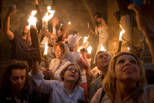 p Faithful hold candles in Jerusalem’s Church of the Holy Sepulcher in this 2014 photo. 