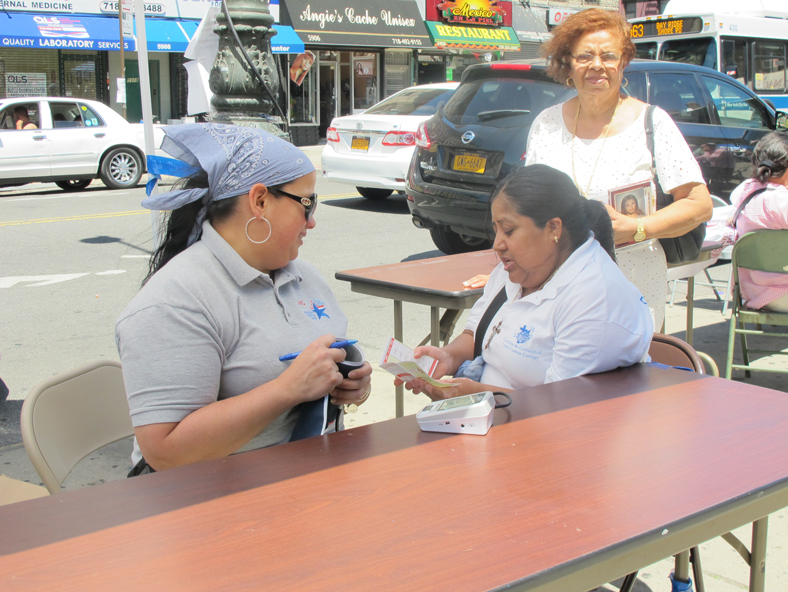 A volunteer with New York City Medical Reserve Corps hands a parishioner a booklet with her blood pressure numbers.