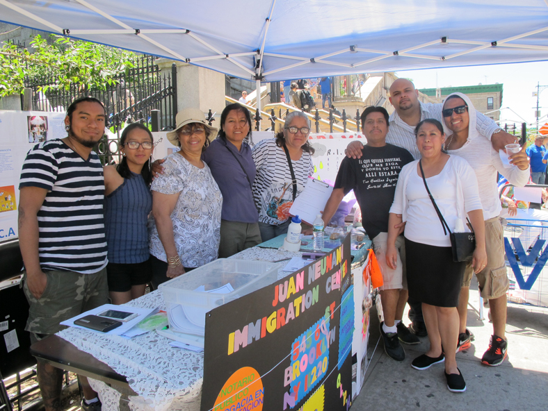 Members of the Juan Neumann Center, which offers immigrants legal help, and the parish’s Spanish-language R.C.I.A. program share a table under a canopy to protect themselves from the hot noontime sun.