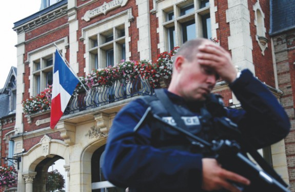 p A policeman reacts as he secures a position in front of city hall after two assailants killed 84-year-old Father Jacques Hamel and took five people hostage during a weekday morning Mass at the church in Saint-Etienne-du-Rouvray, France, near Rouen July 26. (Photo: Catholic News Service/Pascal Rossignol, Reuters) 