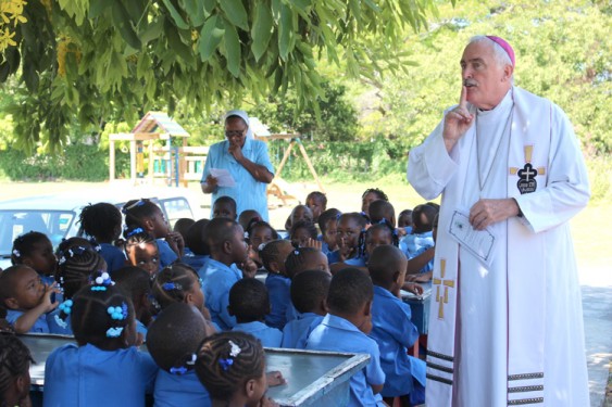 Bishop Tiedemann along with Sister Susan N’gendo, A.S.N., of St. Theresa Kindergarten School, encourage the students to listen quietly.