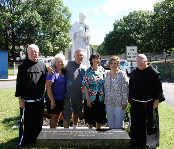 p Brother Leonard Conway, O.S.F., left, and Brother James McVeigh, O.S.F., are joined by members of the DeMarinis family at the statue of St. Francis that once graced the school’s Butler St. site. (Photo: St. Francis Prep)
