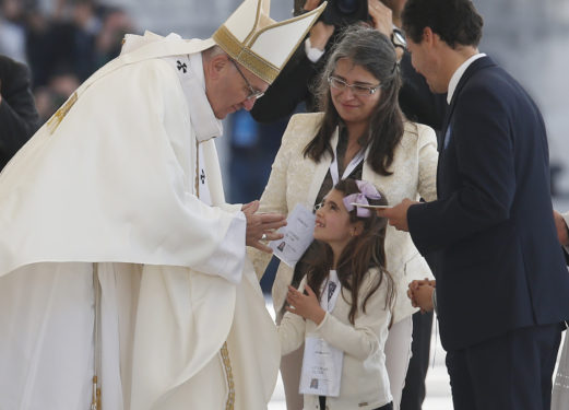 Pope Francis accepts offertory gifts during the canonization Mass of Sts. Francisco and Jacinta Marto, two of the three Fatima seers, at the Shrine of Our Lady of Fatima in Portugal May 13. The Mass marked the 100th anniversary of the Fatima Marian apparitions, which began on May 13, 1917. (CNS photo/Paul Haring)