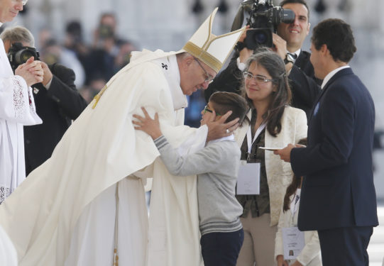 Pope Francis embraces a boy as family members present offertory gifts during the canonization Mass of Sts. Francisco and Jacinta Marto, two of the three Fatima seers, at the Shrine of Our Lady of Fatima in Portugal May 13. The Mass marked the 100th anniversary of the Fatima Marian apparitions, which began on May 13, 1917. (CNS photo/Paul Haring) 